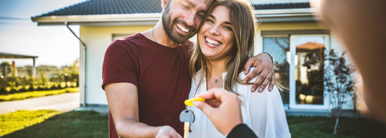 Een gelukkig jong stel krijgt de sleutels overhandigt van hun nieuwe huis